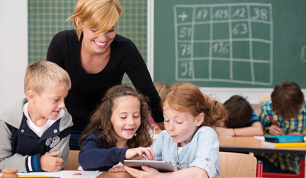 Three-happy-young-students-using-a-tablet-in-class-exclaiming-in-awe-at-the-information-on-the-scree