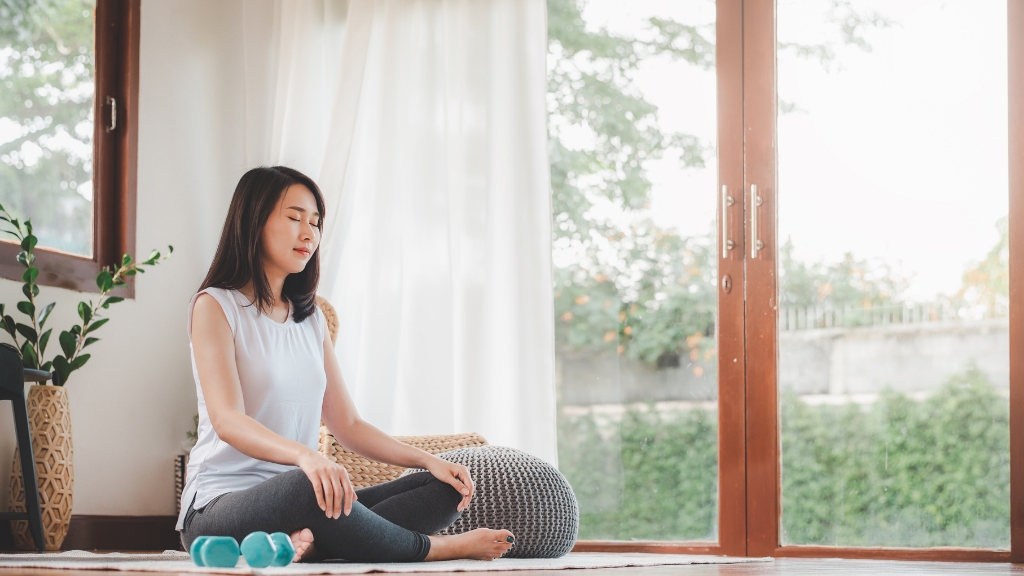 座って目を閉じ、ストレスマネジメントのために呼吸を深めてマインドフルネスを練習している女性